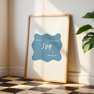 Könnte beinhalten: Ein gerahmter Druck mit blauem Hintergrund und weißem Text, der "Jesus zuerst, andere zweitens, du selbst zuletzt" lautet, mit einem Pfeil, der auf das Wort "Freude" in der Mitte zeigt.