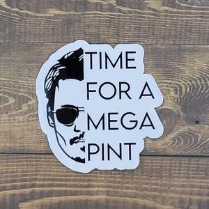 May include: A white sticker with a black and white illustration of a man with sunglasses and a beard. The text "TIME FOR A MEGA PINT" is printed on the sticker.