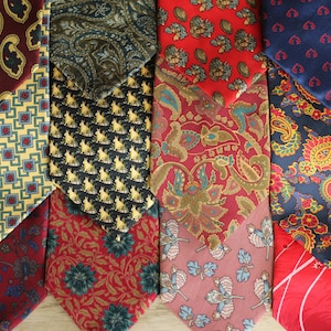 May include: A selection of patterned neckties in various colours. The ties feature designs such as paisley, floral, and geometric patterns. Colours include red, blue, yellow, and green. The ties are arranged side by side, showcasing the variety of styles.