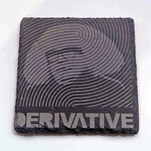 Może przedstawiać: Czarny podkładka z łupka z abstrakcyjnym wzorem w kolorze szarym i białym oraz napisem "DERIVATIVE" nadrukowanym na biało.
