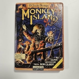 May include: A vintage "Monkey Island 2: LeChuck's Revenge" graphic adventure game box. The box art features a pirate with a beard, a ship, and the game's title in yellow and blue. From Ron Gilbert, LucasArts.