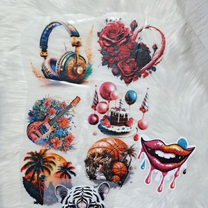 Könnte beinhalten: Ein Set mit acht Bügelbildern mit verschiedenen Designs, darunter ein Kopfhörer, ein Strauß roter Rosen, eine Geburtstagstorte mit Ballons, eine Gitarre mit Blumen, ein Basketball, ein Paar Lippen, eine Palme und ein Tigergesicht.