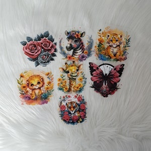 Könnte beinhalten: Satz mit sechs bunten Bügelbildern mit verschiedenen Tier- und Blumenmotiven. Die Patches beinhalten eine Giraffe, einen Schmetterling, einen Löwen, ein Zebra, einen Tiger und eine Rose.