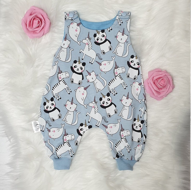 May include: A light blue baby onesie with a white and black animal print. The animals include a zebra, unicorn, narwhal, cat, and panda.