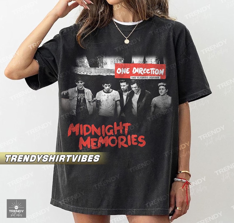 A person wearing a black t-shirt with a graphic design featuring the members of the British pop group One Direction.
