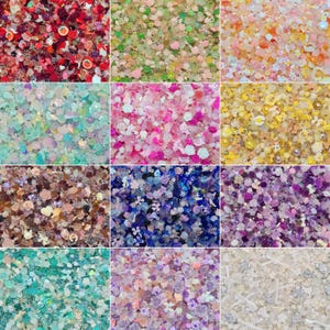 May include: A selection of craft glitter in a variety of colours and textures. The glitter includes shapes such as flowers, stars, and other decorative elements. Colours range from red, pink, and green to blue, purple, and gold. Suitable for scrapbooking, nail art, and other craft projects.