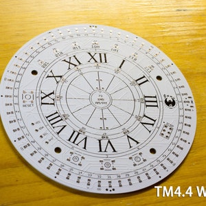 May include: A white circular electronic circuit board with Roman numerals marking the hours. The board has numerous small components and the text "TM4.4 White". The design includes the text "RESET" and other technical markings.