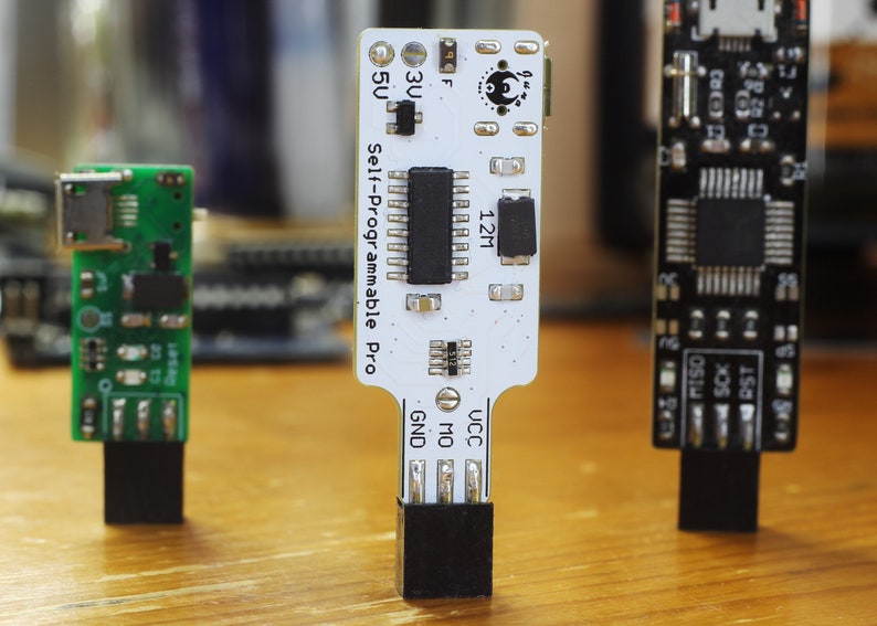 May include: Three small circuit boards with black connectors. The centre board is white with black text that reads "Self-Programmable Pro" and "12M". The board on the left is green and the board on the right is black.