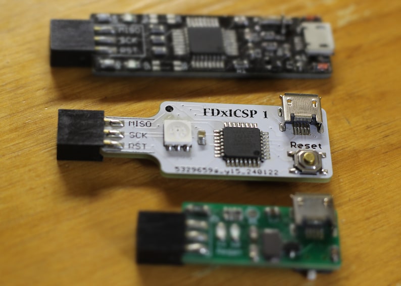 May include: Three small circuit boards with microchips, connectors, and buttons. The top board is black, the middle board is white with the text "FDXiCSP 1", and the bottom board is green.