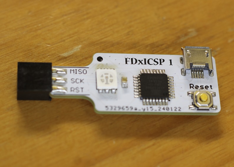 May include: A white circuit board with a black chip, a small LED, and a micro USB connector. The board is labelled "FDxICSP 1" and has a reset button.