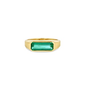 May include: A gold ring with a rectangular emerald green gemstone.