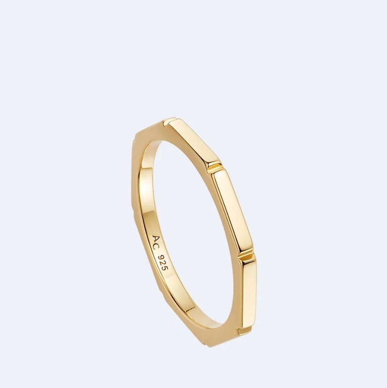 May include: A gold ring with a hexagonal band. The ring is marked with "AC 925" on the inside.