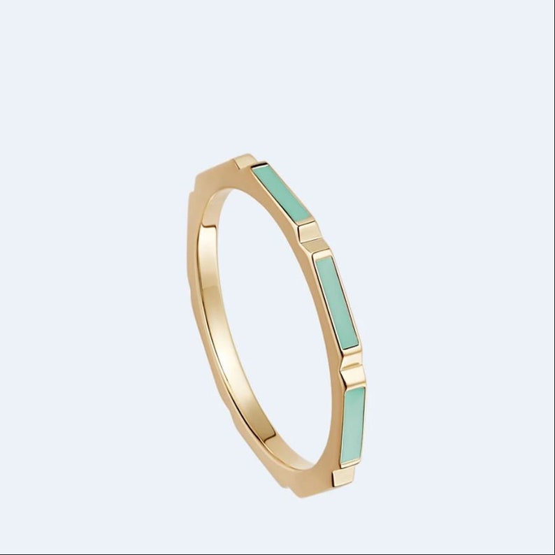 May include: A gold ring with a geometric design and light blue enamel accents.