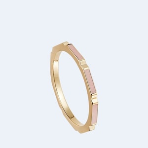 May include: A gold ring with a pink enamel design. The ring has a geometric shape and is set with a row of pink enamel.