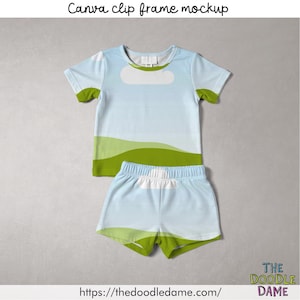 Puede incluir: Conjunto de camiseta y pantalón corto azul claro con diseño de paisaje. La camiseta tiene una forma de nube blanca y detalles verdes en las mangas y la parte inferior. El pantalón corto tiene un diseño a juego con cintura blanca y ribete verde.