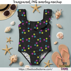 Puede incluir: Un ba&ntilde;ador negro con un estampado de estrellas de colores. El ba&ntilde;ador tiene un escote con volantes y est&aacute; rodeado de conchas marinas, estrellas de mar, gafas de sol y chanclas. El texto "Transparent PNG overlay mockup" est&aacute; en la parte superior.