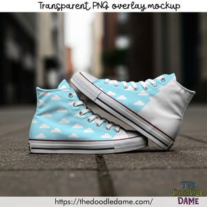 May include: A pair of high-top sneakers with a light blue sky and white cloud pattern. The shoes have white laces, a white toe cap, and a white heel. The soles are white with a red and navy blue stripe.