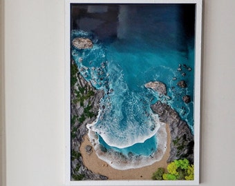 Puede incluir: Una pieza de arte de resina enmarcada que representa una escena de playa con un océano azul turquesa, olas blancas espumosas y una playa de arena con vegetación verde.