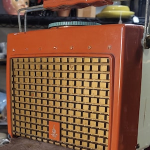 May include: Vintage orange and white Emerson portable radio with a metal carrying handle and a gold speaker grille. The radio has a round dial with a green and white design.