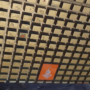 May include: A vintage orange and gold radio with a grid pattern on the front. The radio has a small orange label with the text "LOMAX" in white.