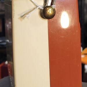 May include: A vintage portable radio with a white and orange plastic case. The radio has a metal carrying handle and a gold knob.
