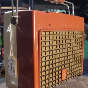 May include: A vintage orange and white Emerson 7710  'Jazz AC/DC'  Radio Dial. The radio has a gold speaker grille with a small Emerson logo.