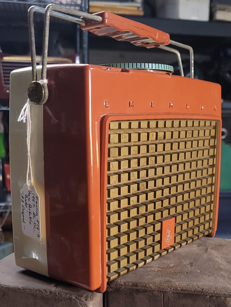 May include: A vintage orange and white Emerson 7710  'Jazz AC/DC'  Radio Dial. The radio has a gold speaker grille with a small Emerson logo.
