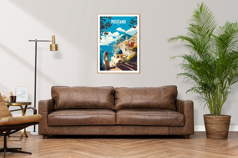 May include: A framed poster with a colorful illustration of Positano, Italy. The poster features a blue sky, white buildings, and a blue domed church. The text "Positano" is printed in white on a blue background at the top of the poster.