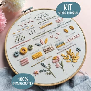 Könnte beinhalten: Ein Stickrahmen mit weißem Stoff, der verschiedene gestickte Muster und Beschriftungen wie Straight Stitch, Back Stitch, Lazy Daisy, Cross Stitch, Chain Stitch, Woven Oval, French Knot, Pistil Stitch, Stem Stitch, Fly Stitch und Blanket Stitch enthält.