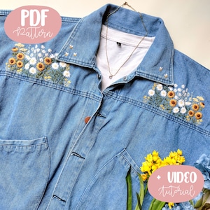 May include: Light blue denim jacket with embroidered sunflowers and daisies. The jacket has a button-up front, a chest pocket, and a collar. The text "PDF Pattern" is in a pink circle. A gold necklace is visible.