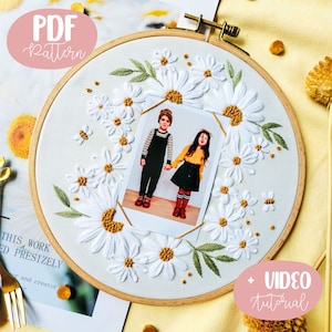Peut inclure: Art de broderie sur cercle représentant une couronne de marguerites blanches avec une photo de deux enfants à l'intérieur. Le cercle est en bois et a une finition naturelle. La photo est une photo instantanée de style Polaroid avec une bordure blanche. Le texte "PDF Pattern" et "VIDEO tutorial" sont également inclus dans l'image.
