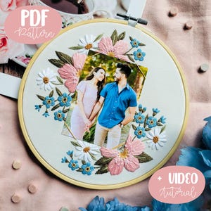 Może przedstawiać: Białe tamborek do haftu z fotografią pary otoczonej haftowanymi różowymi, białymi i niebieskimi kwiatami. Tekst "PDF Pattern" jest w kolorze różowym po lewej stronie obrazu, a "VIDEO tutorial" jest w kolorze różowym po prawej stronie obrazu.