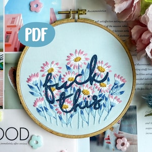 Pode incluir: Arte de aro bordado com um design floral de margaridas rosa e brancas e folhas azuis. A frase "fuck this" é bordada em itálico azul escuro. O aro é de tecido azul claro com uma moldura de madeira. Um ícone PDF está no canto superior esquerdo.