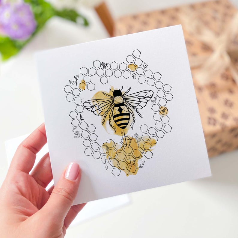 May include: A black and white illustration of a bee in a honeycomb heart shape. The honeycomb is outlined in black and filled with a yellow watercolor wash.