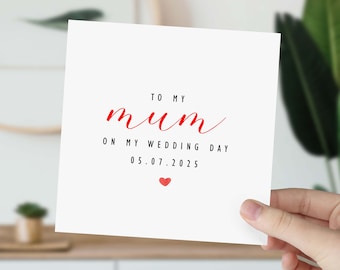 Peut inclure: Carte blanche avec du texte rouge qui dit "To my mum on my wedding day 05.07.2025" avec un petit cœur rouge.