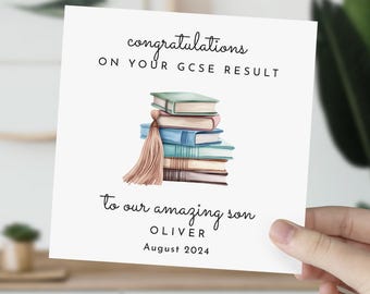 May include: A white card with the text "congratulations on your GCSE result" and a watercolor illustration of a stack of books with a tassel. The card also says "to our amazing son Oliver August 2024".