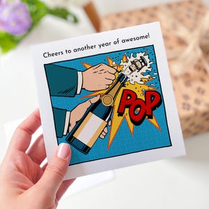 Um brinde a mais um ano de cartão incrível com design pop-art Cartão de feliz aniversário para ela, ele, amigo, marido, esposa, saudações de ano novo