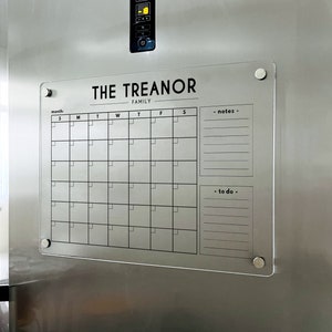 May include: A white dry-erase calendar with the text "THE TREANOR FAMILY" at the top. The calendar has spaces for each day of the week and sections for notes and to-dos.