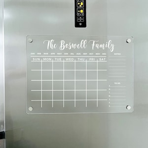 May include: A white acrylic dry-erase calendar with the text "The Boswell Family" at the top. The calendar has spaces for each month of the year, days of the week, notes, and a to-do list.