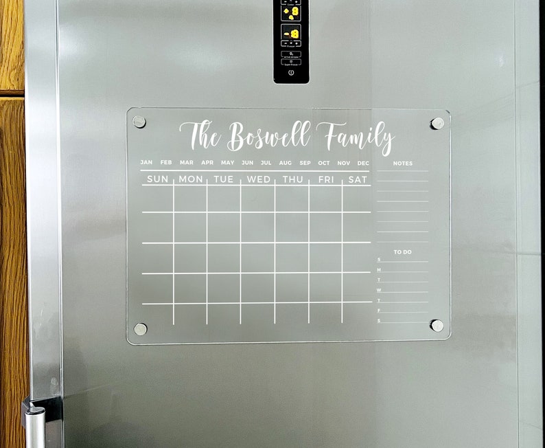 May include: A white acrylic dry-erase calendar with the text "The Boswell Family" at the top. The calendar has spaces for each month of the year, days of the week, notes, and a to-do list.