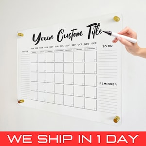 May include: A clear acrylic dry erase calendar with a black and white design. The calendar has a section for notes, a monthly calendar grid, a to-do list, and a reminder section. The calendar is hanging on a wall with gold hooks. The text "Your Custom Title" is at the top of the calendar.