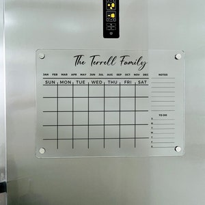 May include: A clear acrylic dry-erase calendar with the text "The Terrell Family" at the top. The calendar has spaces for each month of the year, days of the week, and a to-do list.