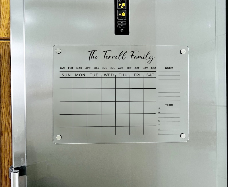 May include: A clear acrylic dry-erase calendar with the text "The Terrell Family" at the top. The calendar has spaces for each month of the year, days of the week, and a to-do list.