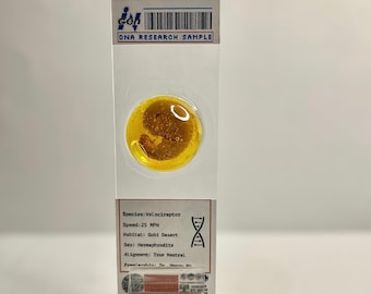 May include: A close-up of a yellow DNA sample labeled "Velociraptor" with details about the species, including speed, habitat, sex, and alignment. The sample is in a clear plastic slide with a black and white barcode label.