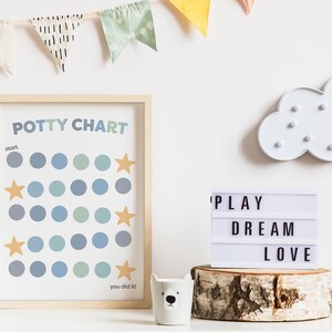 May include: A framed potty chart with blue and green circles and gold stars. The chart says "Potty Chart" and "You did it!"  A white light-up cloud and a white light-up sign that says "PLAY DREAM LOVE" are also in the image.