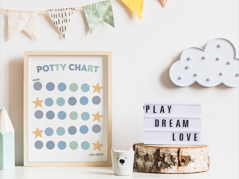 May include: A framed potty chart with blue and green circles and gold stars. The chart says "Potty Chart" and "You did it!"  A white light-up cloud and a white light-up sign that says "PLAY DREAM LOVE" are also in the image.