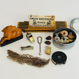 May include: A collection of vintage items including a Smith Brothers cough drop box, a wooden horse figurine, a folding ruler, a metal whistle, a button hook, nail clippers, a padlock with keys, a tin of assorted buttons, and a black tape measure.