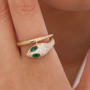 May include: A gold snake ring with green gem eyes and a pave setting of clear stones.