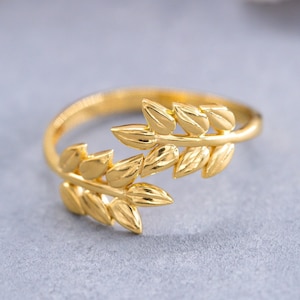 May include: A gold ring with a delicate design of two intertwined branches of leaves.