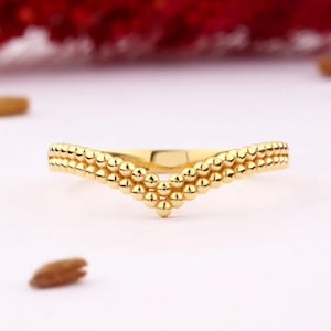 May include: A gold ring with a V-shaped design made of small, round beads.